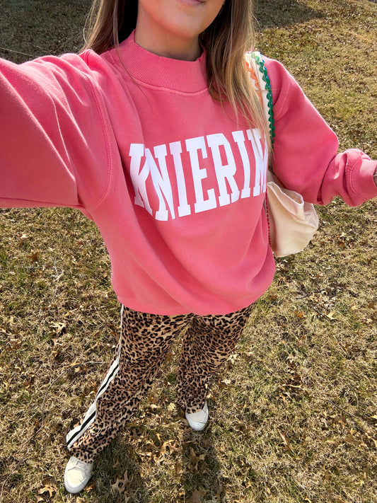 Person wearing a pink sweatshirt with 'KNIERIM' text and leopard print pants outdoors.