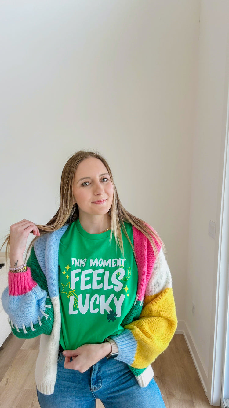 Person wearing a colorful sweater with text, standing indoors.